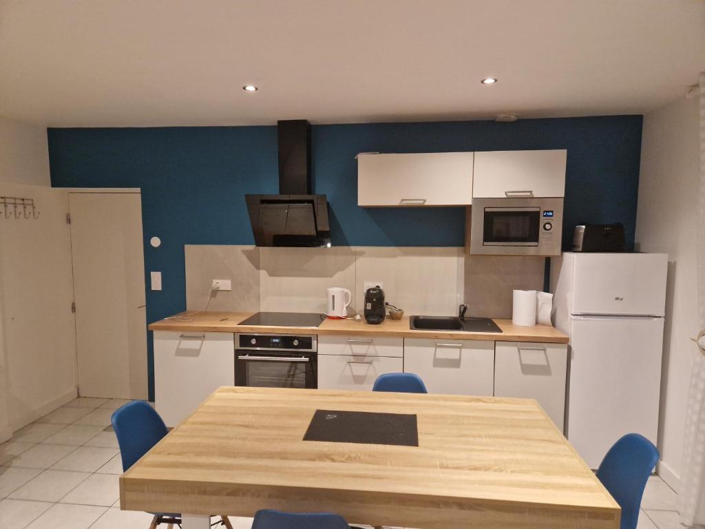 una cucina con tavolo e una cucina con pareti blu di ILEANA a Villefranche-de-Rouergue