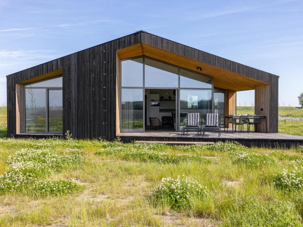 a small black house with two chairs and a table at Nature Escape w Sauna in Wissenkerke