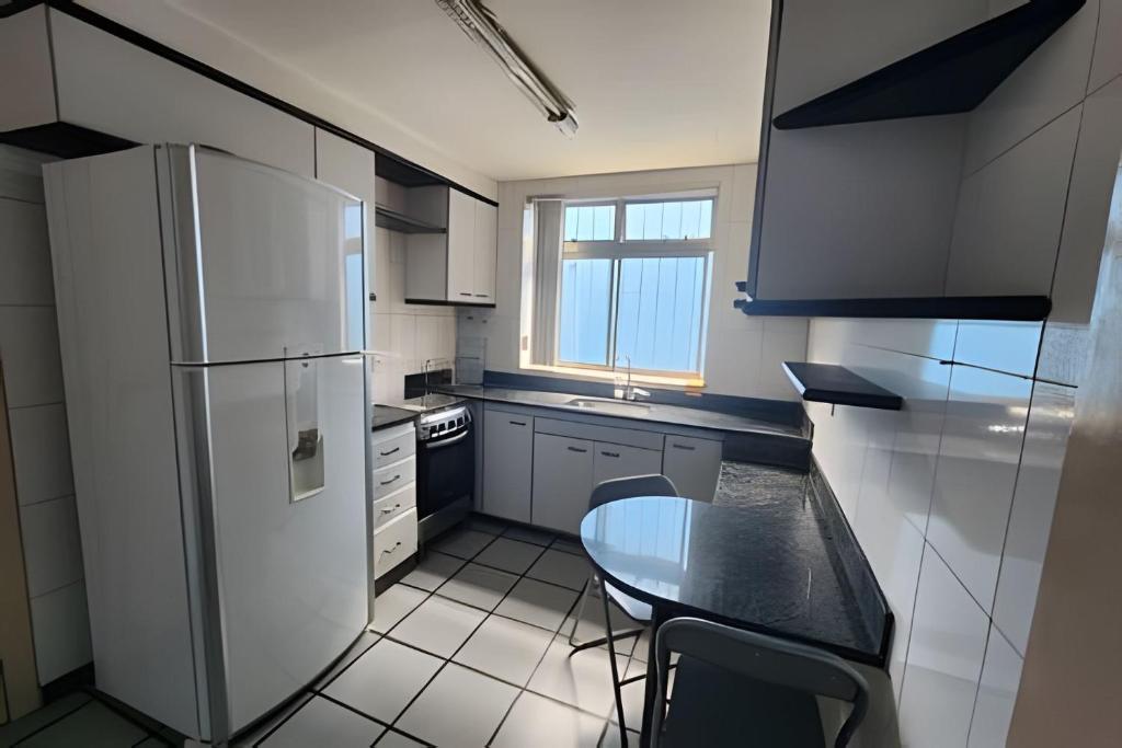 a small kitchen with a table and a refrigerator at Casa segundo andar no Santa Efigênia in Belo Horizonte
