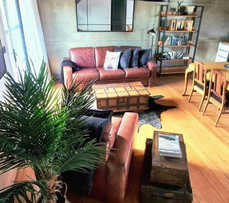 a living room with a leather couch and a table at Apartment 3 - Haddin Court - Industrial Glam in Blenheim