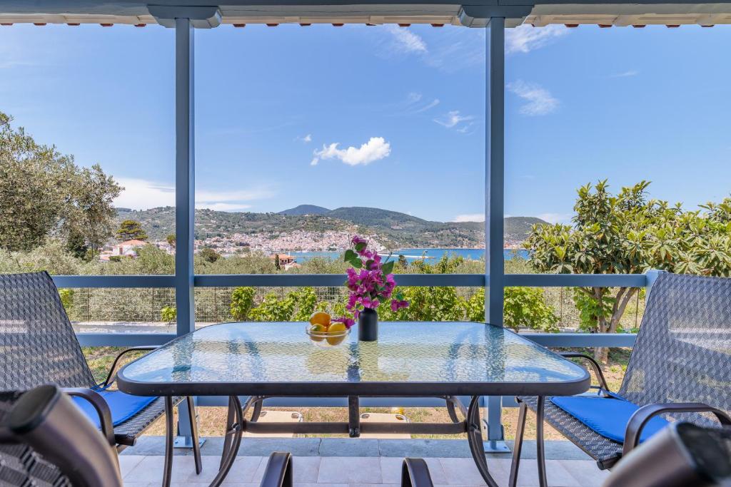 a table with flowers on a balcony with chairs at Anesis Apartment 1 in Panormos Skopelos