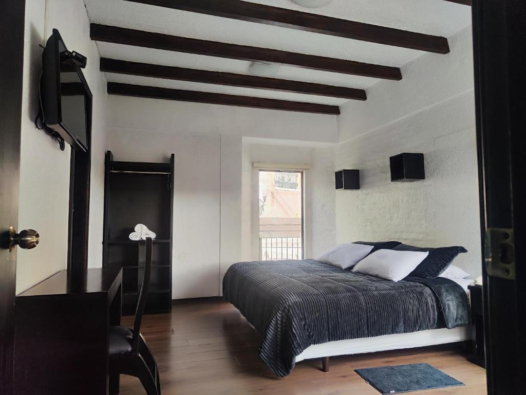 a bedroom with a bed and a ceiling with beams at Hotel Bellavista Quito in Quito