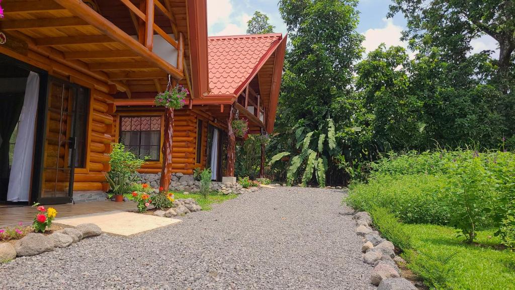 a log cabin with a walkway next to a house at Arenal Sweet Cabins in Fortuna
