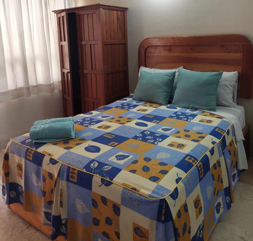 a bed with a blue and yellow quilt on it at Hotel Kootznoowoo in Puerto Escondido