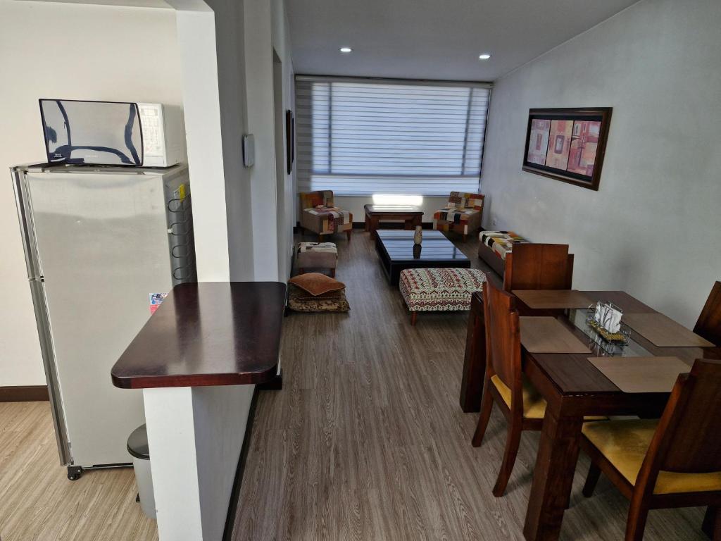 Apartamento La Floresta con todas las comodidades في بوغوتا: مطبخ وغرفة طعام مع ثلاجة وطاولات