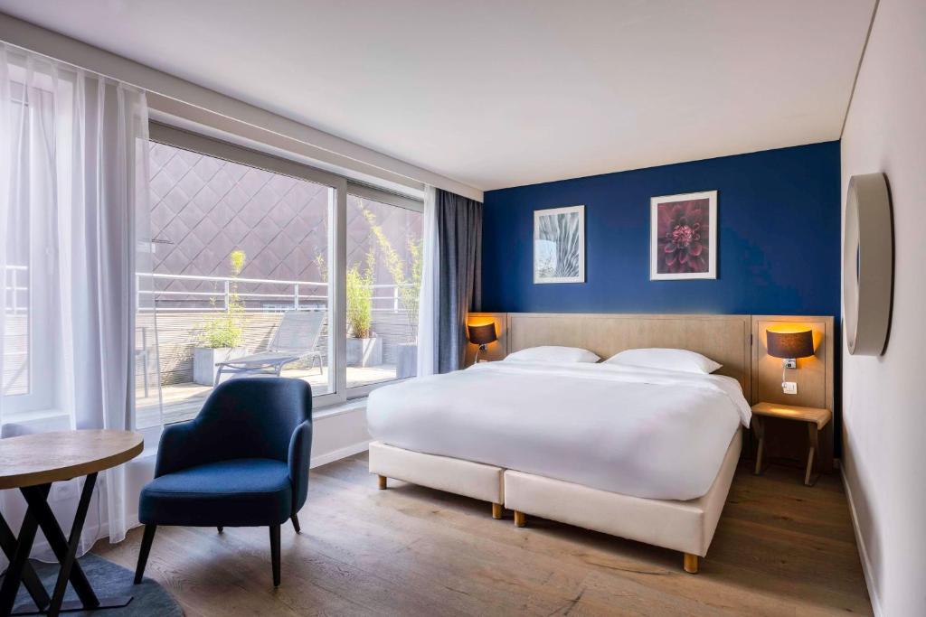 een slaapkamer met een bed, een tafel en een stoel bij Park Inn by Radisson Antwerp City Centre in Antwerpen