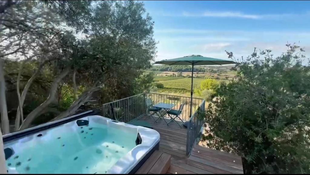 a hot tub on a deck with an umbrella at Lodge Paradisiaque Spa in Cazouls-lès-Béziers