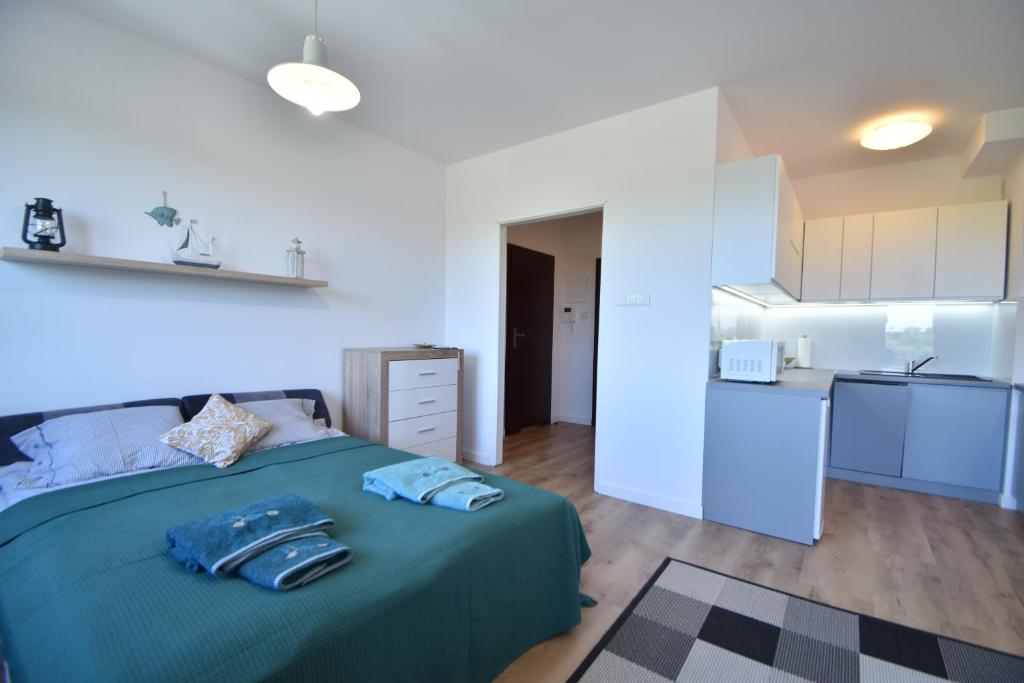 Cet appartement comprend une chambre avec un lit vert et une cuisine. dans l'établissement City Dwor Apartament, à Gdańsk