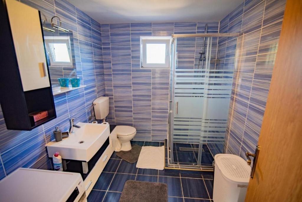 a blue tiled bathroom with a toilet and a sink at Family friendly house with a swimming pool Dazlina, Sibenik - 23303 in Tisno