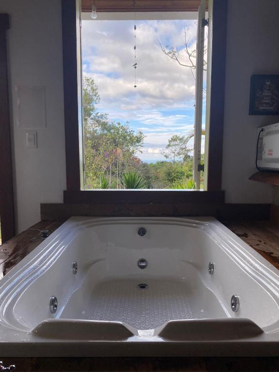 a large bath tub in a room with a window at Chalés Lavras de Minas - Amar in Lavras Novas