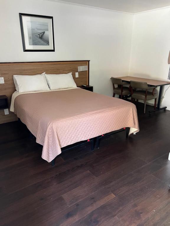 1 dormitorio con 1 cama grande y 1 mesa en Cadet Motel en Cornwall-on-Hudson