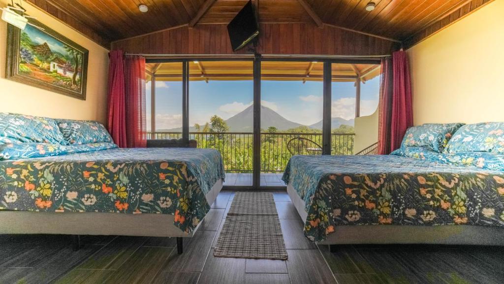 a bedroom with two beds and a balcony at Villas Paradise in El Castillo de La Fortuna