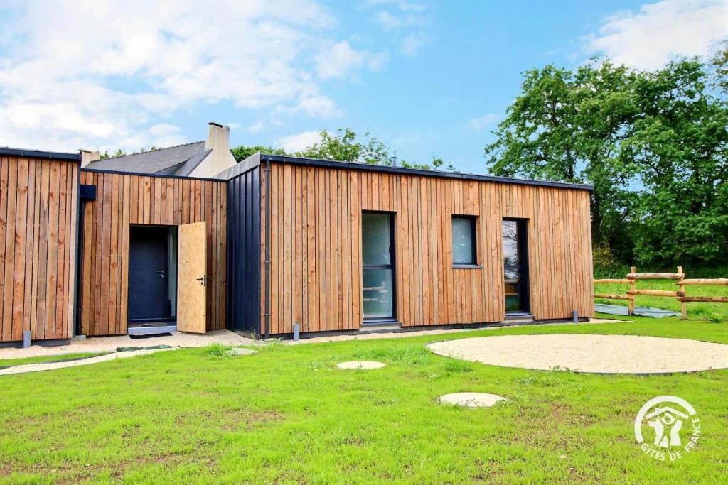 a wooden house in a field with a grass yard at Les asphodeles in Muzillac
