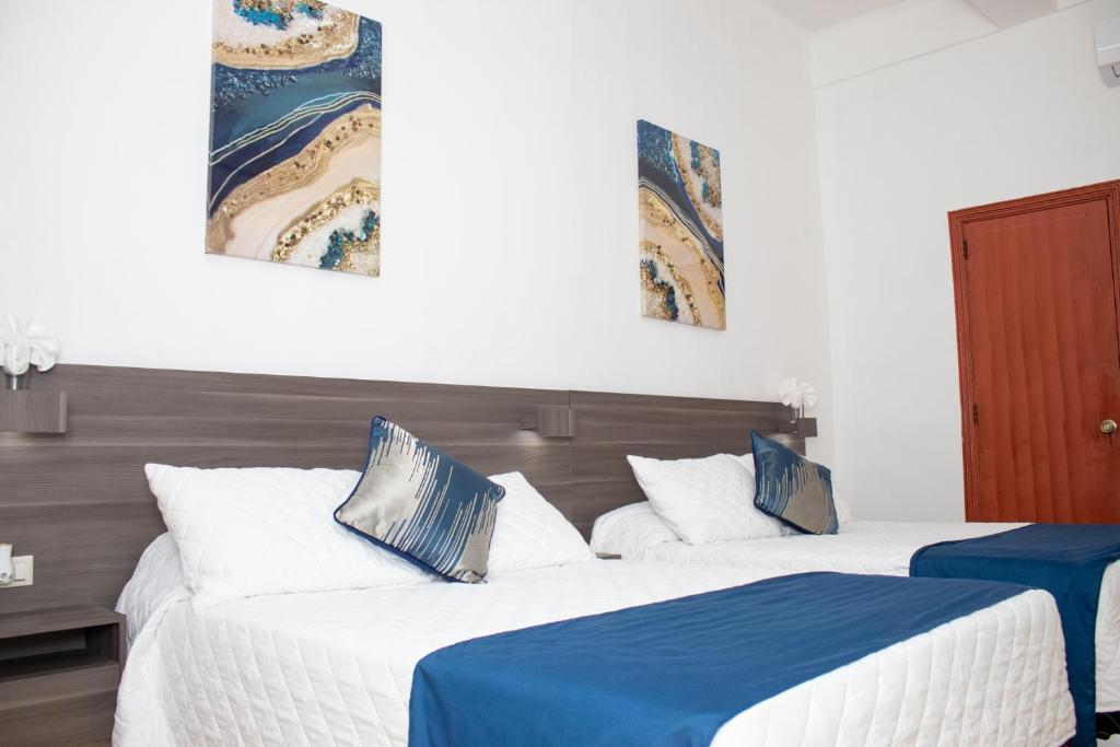 dwa łóżka w pokoju niebiesko-białym w obiekcie Kali Hotel w mieście Santa Ana