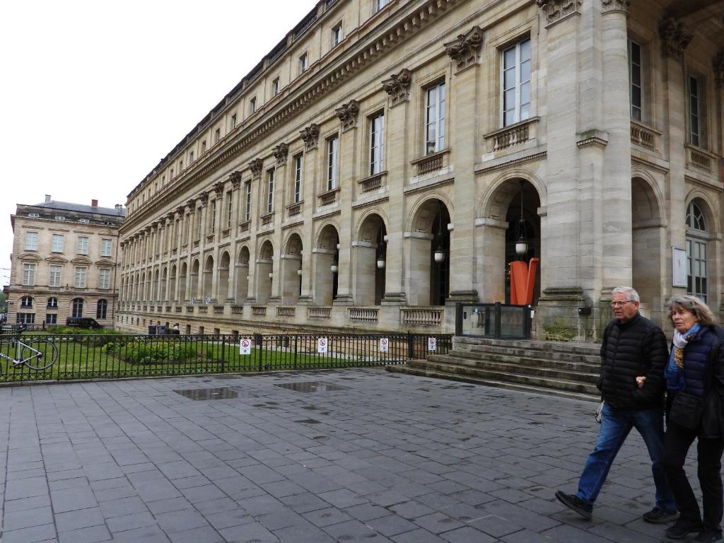 two people walking in front of a large building at B&B Le Miroir aux Fées Bordeaux in Bordeaux