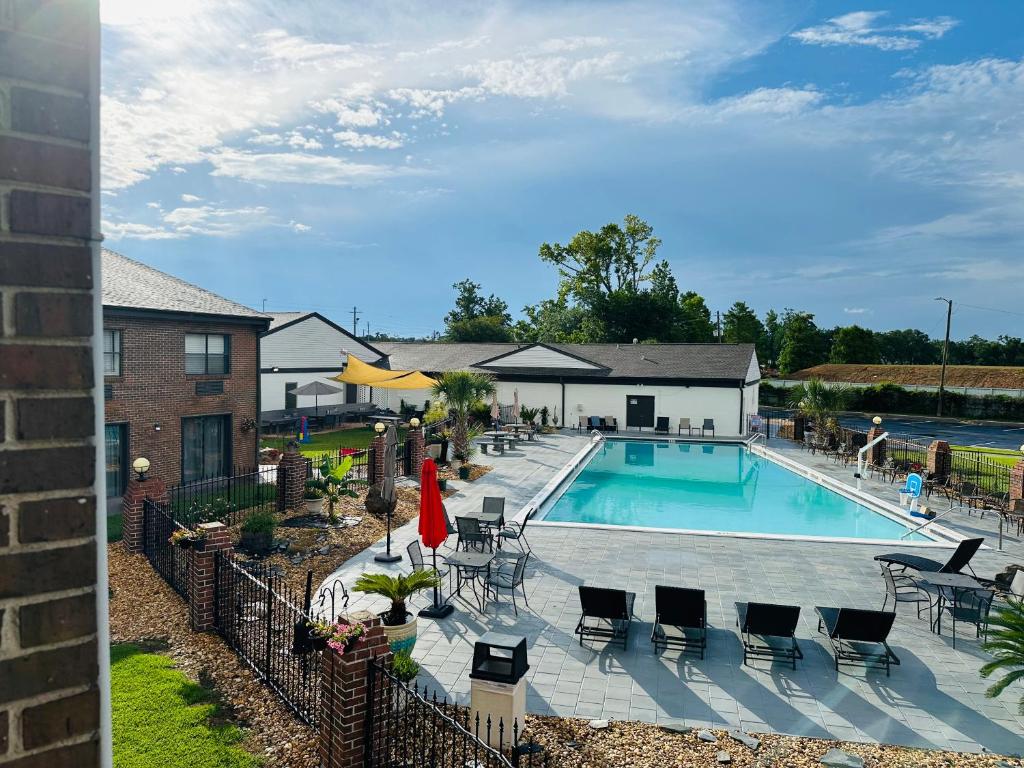 una piscina con muebles de exterior y un edificio en At Home Inn - Pensacola, en Pensacola