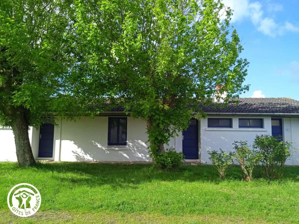 une maison blanche avec un arbre dans la cour dans l'établissement Gîte 2 pers. proche plages et Marais Poitevin, terrasse couverte, tout inclus - FR-1-426-551, à Saint-Michel-en-lʼHerm