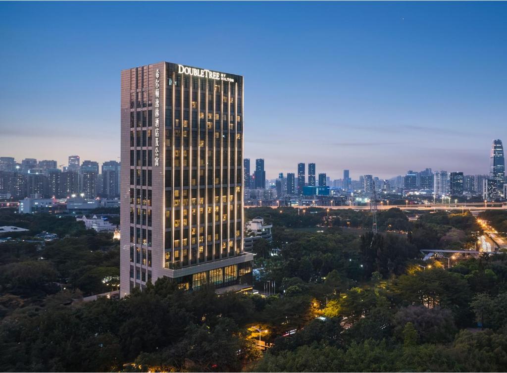 DoubleTree By Hilton Shenzhen Nanshan Hotel & Residences في شنجن: مبنى طويل مع أضواء على مدينة