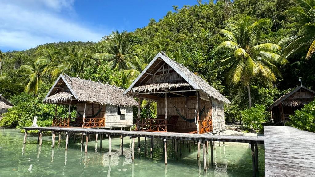 Pulau MansuarにあるNyande Raja Ampatの水上の桟橋の小屋2棟