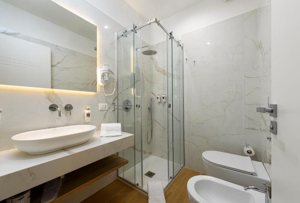 a bathroom with a sink and a glass shower at Andromeda Hotel in San Vito lo Capo