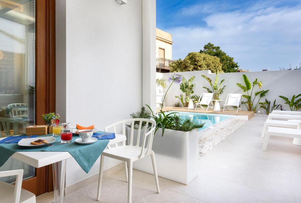 a balcony with a table and chairs and a swimming pool at Andromeda Hotel in San Vito lo Capo