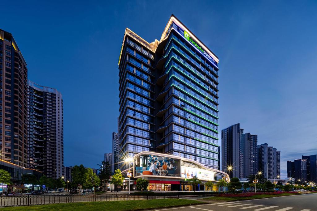 un grand bâtiment dans une ville avec de grands bâtiments dans l'établissement Holiday Inn Express Jiangmen East Station, an IHG Hotel, à Jiangmen