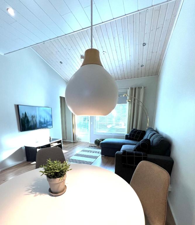 ein Wohnzimmer mit einem Tisch und einer Hängeleuchte in der Unterkunft Ihana huoneisto - The Nest with Sauna in VAASA in Vaasa