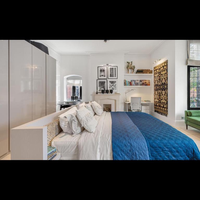 een slaapkamer met een groot bed en een blauwe deken bij Luxury Suite in Cadogan Square II in Londen