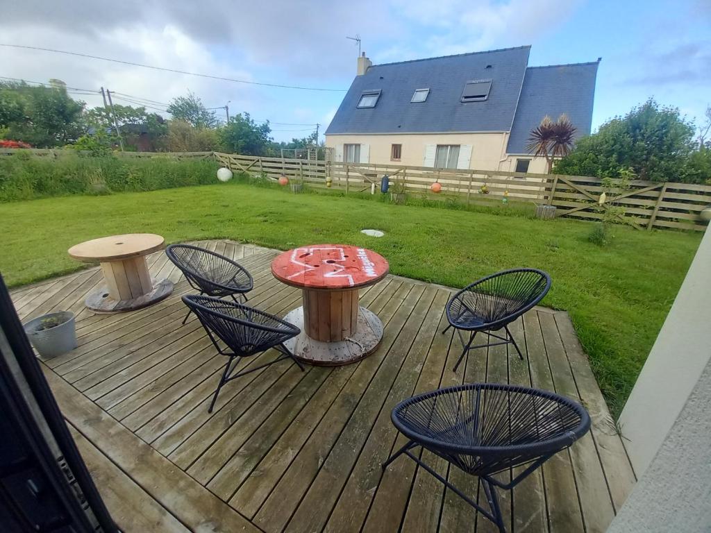 une terrasse en bois avec une table et des chaises dessus dans l'établissement Gite de Kerizouarn, à Lampaul-Plouarzel