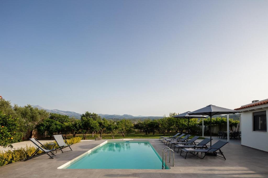 a swimming pool with chairs and an umbrella at Angeliana Villa in Angeliana