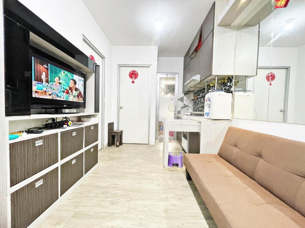 Cozy 2BR Apt with direct access to Mall @Green Bay Pluit Apartment في جاكرتا: غرفة معيشة مع أريكة وتلفزيون بشاشة مسطحة