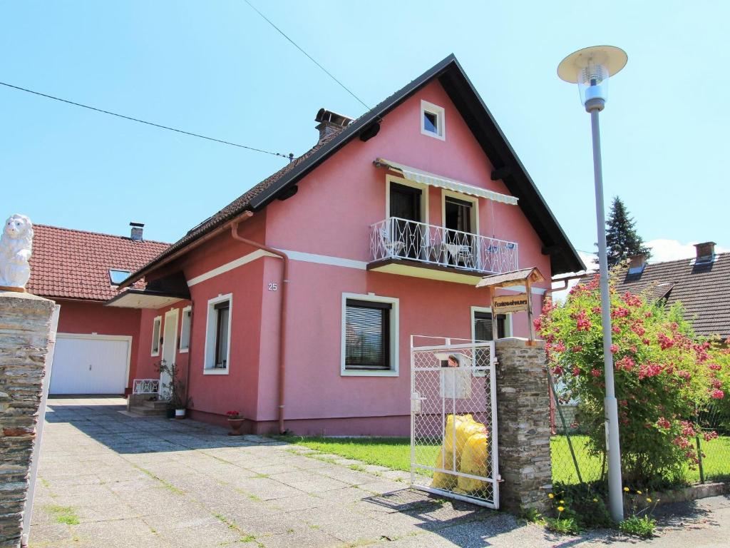 uma casa cor-de-rosa com uma vedação à frente. em Modern apartment with garden near the Petzen ski area in Eberndorf Carinthia em Eberndorf