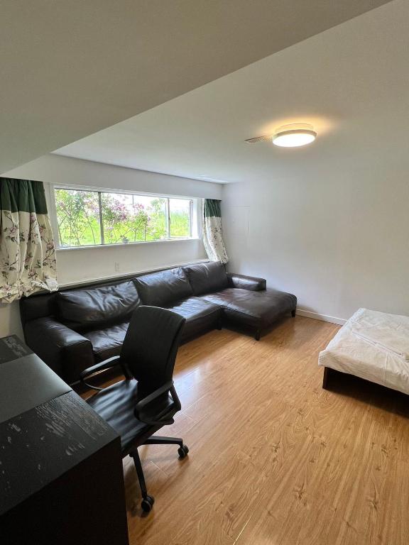 a living room with a black leather couch and a bed at Green House in Vancouver West in Vancouver