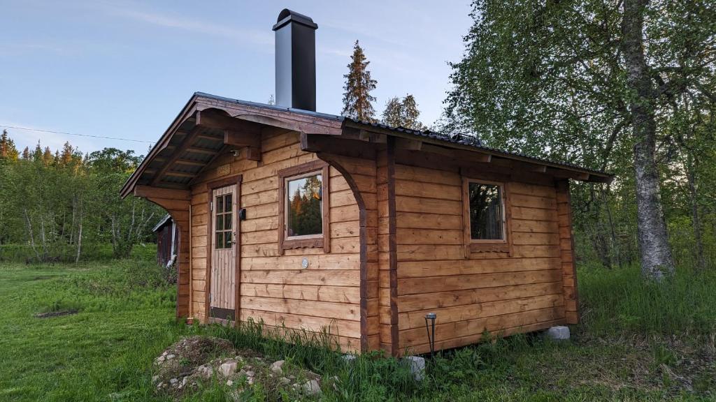 a wooden cabin in a field with a chimney at Lapland Snow Moose in Vittangi Kapell