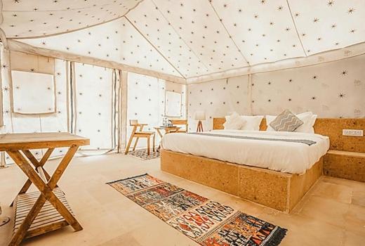 1 dormitorio con 1 cama y 1 mesa en una habitación en Jaisan Boutique Desert Camp Jaisalmer, en Jaisalmer