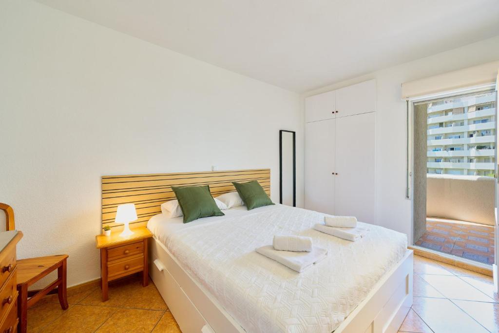 1 dormitorio blanco con 1 cama grande con almohadas verdes en Benalbeach playa - Tu hogar frente al mar, complejo 4 piscinas, en Arroyo de la Miel