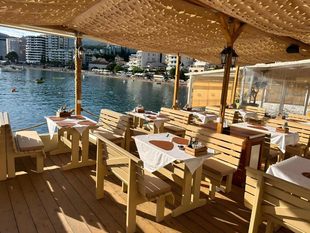 a restaurant with tables and chairs and a view of the water at Hotel Kuč in Budva