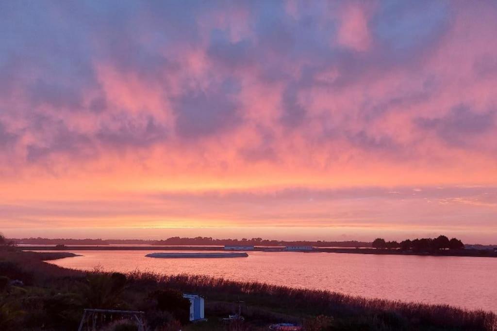 un coucher de soleil sur une rivière avec un bateau dans l'eau dans l'établissement Villa de vacances au bord de mer, à l'Île-Tudy