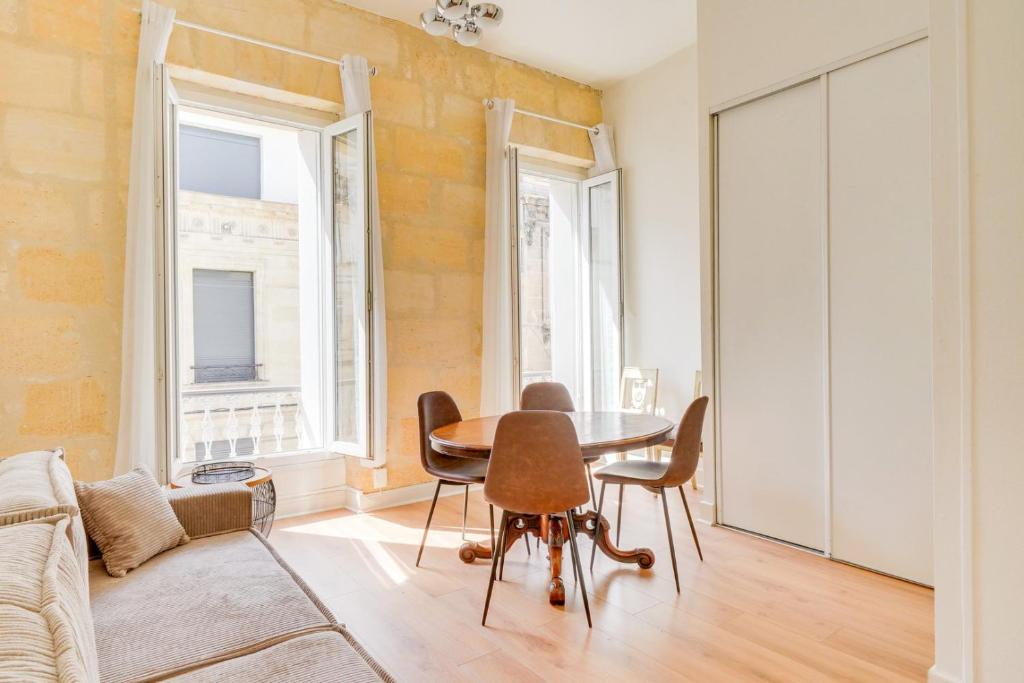 un salon avec une table, des chaises et un canapé dans l'établissement Bel appartement proche Victoire, à Bordeaux