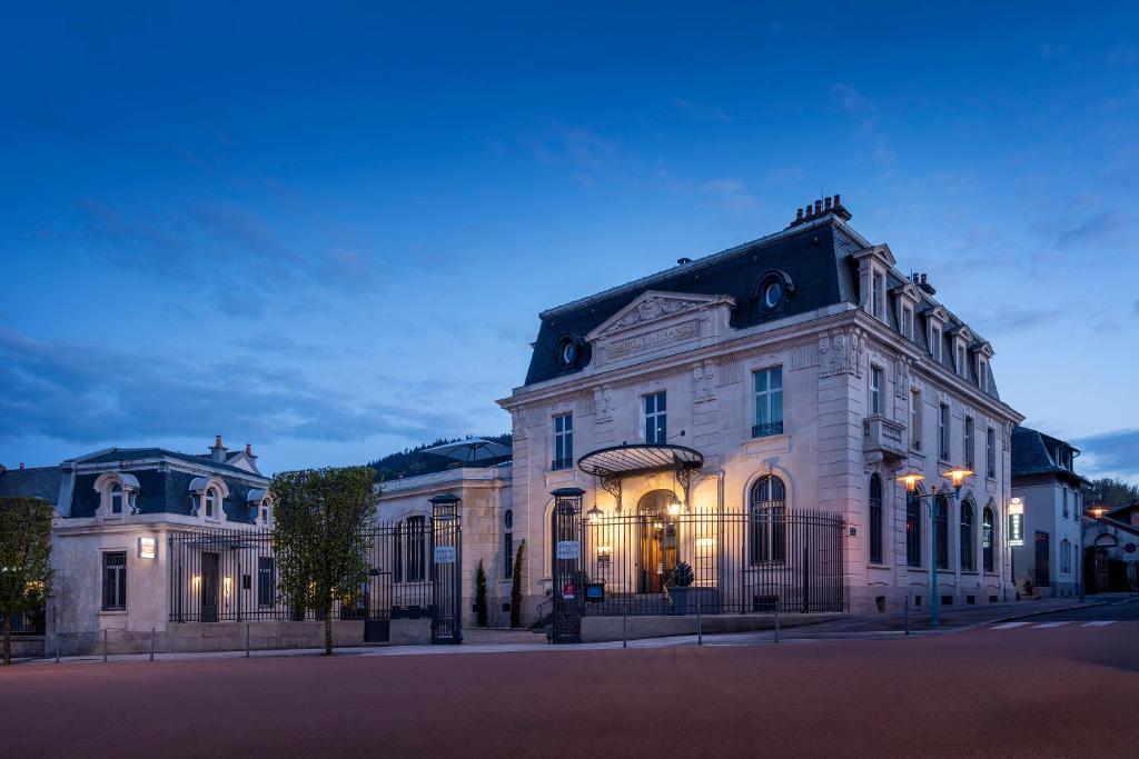 um grande edifício branco numa rua à noite em Best Western Premier Le Chapitre Hotel and Spa em Remiremont