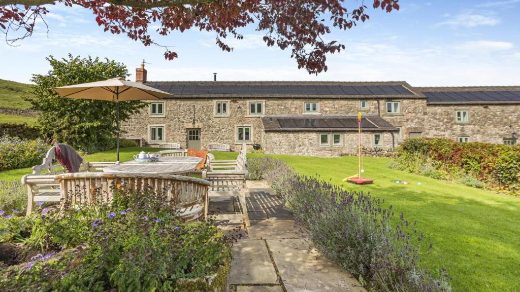 una vista exterior de una casa de piedra con sombrilla en New Harborough Farm en Brassington