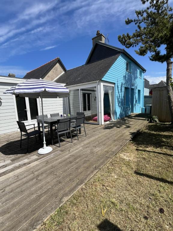 une terrasse en bois avec une table et un parasol dans l'établissement Skol Ar Louarn - Maison de vacances Ile-grande, à Pleumeur-Bodou