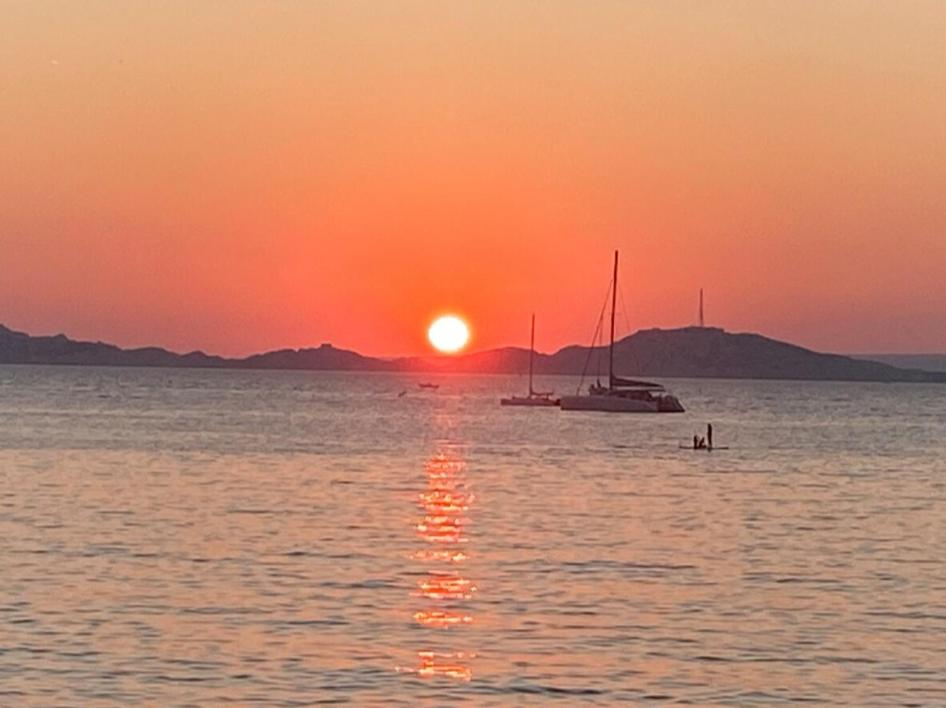 un bateau dans l'eau avec un coucher de soleil en arrière-plan dans l'établissement Maison bord de mer avec jacuzzi, à Marseille