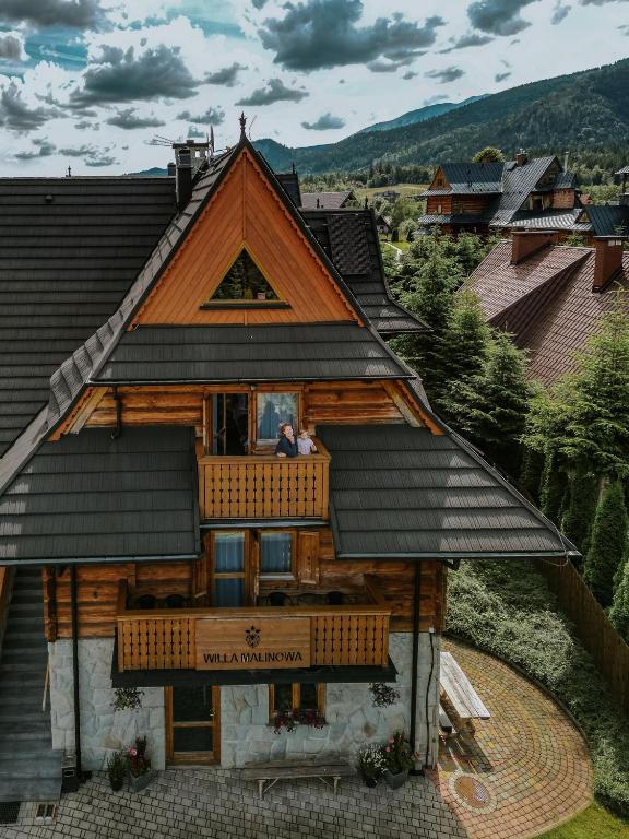 a couple sitting on the balcony of a house at Willa Malinowa in Zakopane