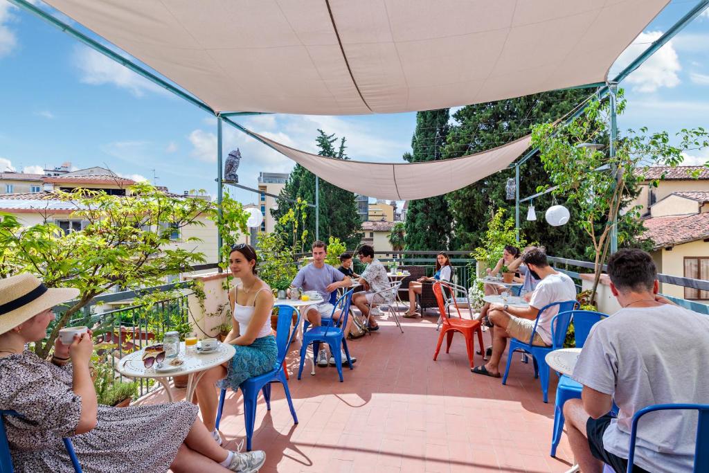 een groep mensen die aan een tafel op een patio zitten bij Ostello Bello Firenze in Florence