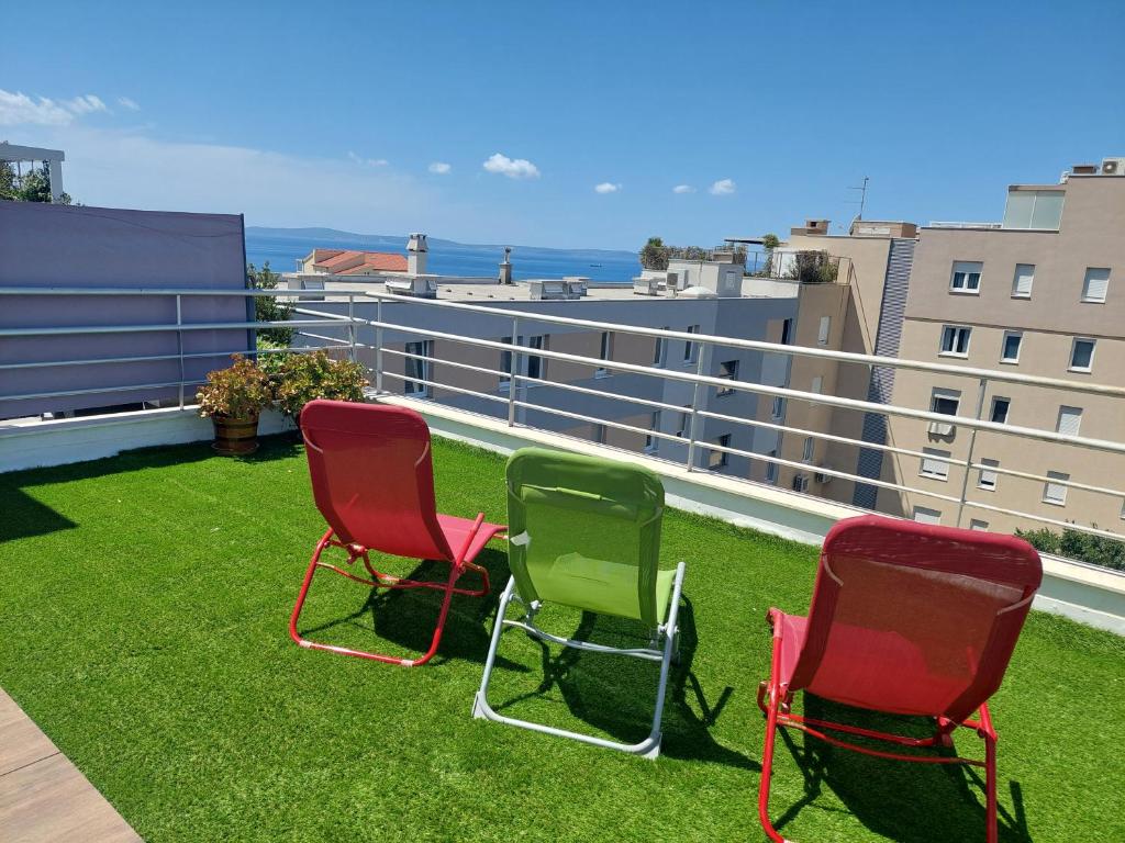 three chairs sitting on the grass on a balcony at Penthouse Znjan in Split