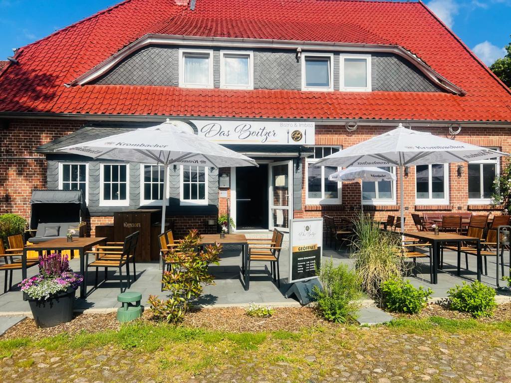 a restaurant with tables and umbrellas in front of a building at Das Boitzer in Walsrode