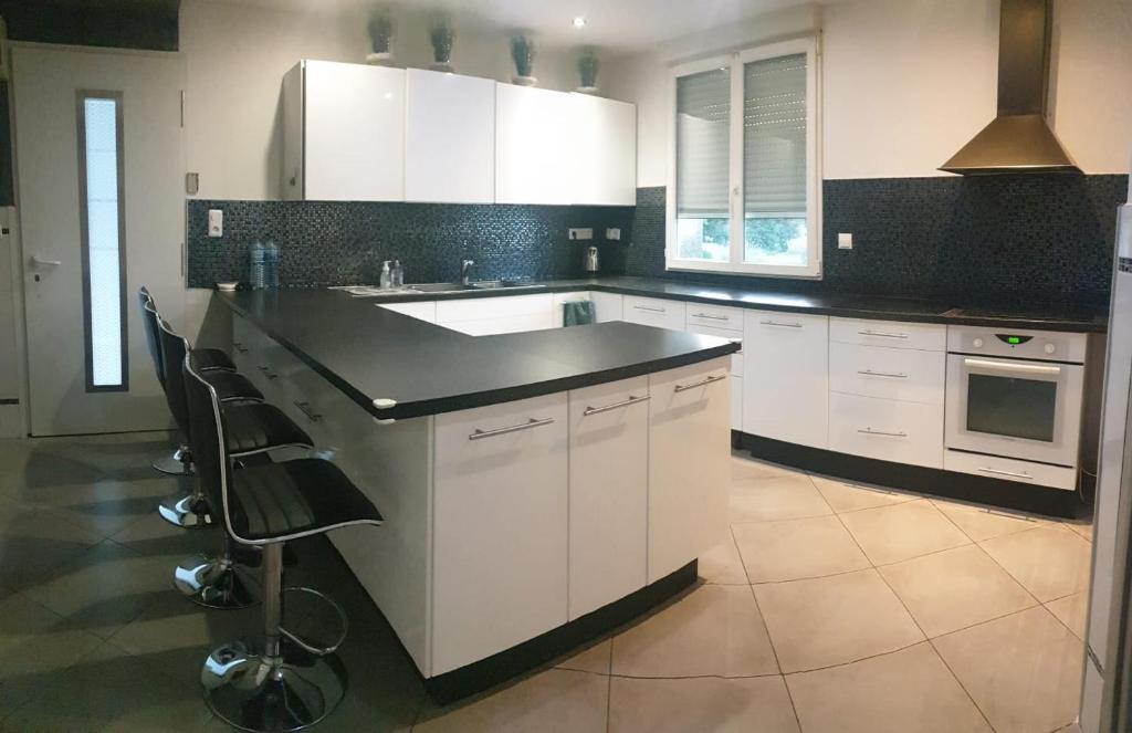 une cuisine avec des armoires blanches et un comptoir noir dans l'établissement Super villa, à Le Crès