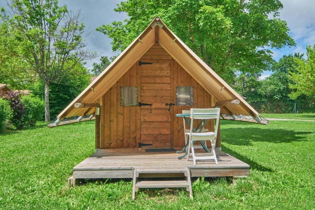 une maison avec une chaise et une table dans l'herbe dans l'établissement Caravane Tente 2 places, à Mens
