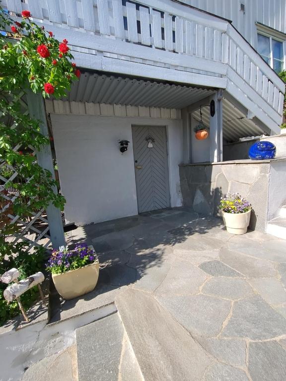 a white garage with two potted plants on a patio at Koselig liten leilighet med hyggelig uteplass in Kragerø